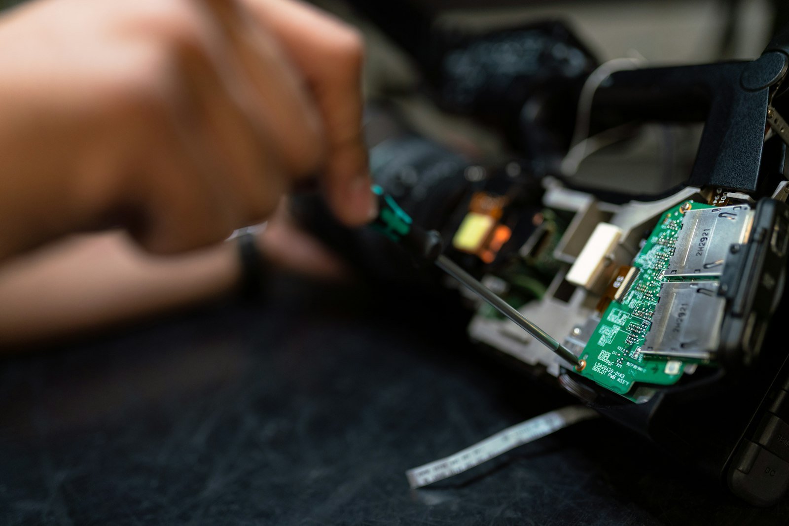 Repair technician holding a circuit board over an electronics workbench